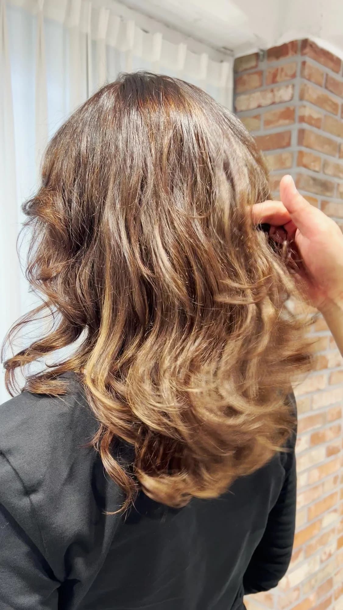 Soft caramel curls after a Korean perm, seen from the back